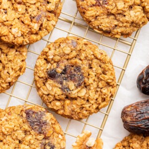 Oatmeal date cookies on a gold wire cooling rack.