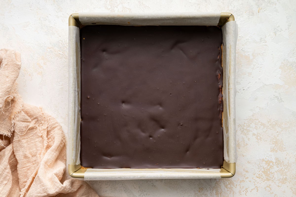 Peanut butter bars uncut in a 8x8 square baking dish after chilling in the fridge.