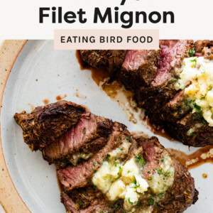 Two Air Fryer Filet Mignons on a plate, sliced and topped with herb butter.