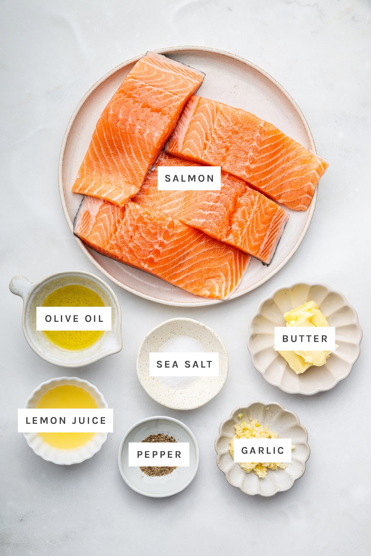 Ingredients measured out to make Garlic Butter Pan Seared Salmon: salmon, olive oil, sea salt, butter, lemon juice, pepper and garlic.