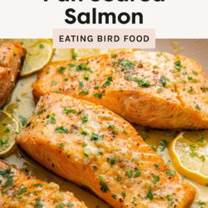 Garlic Butter Pan Seared Salmon in a skillet with parsley and lemon for garnish.