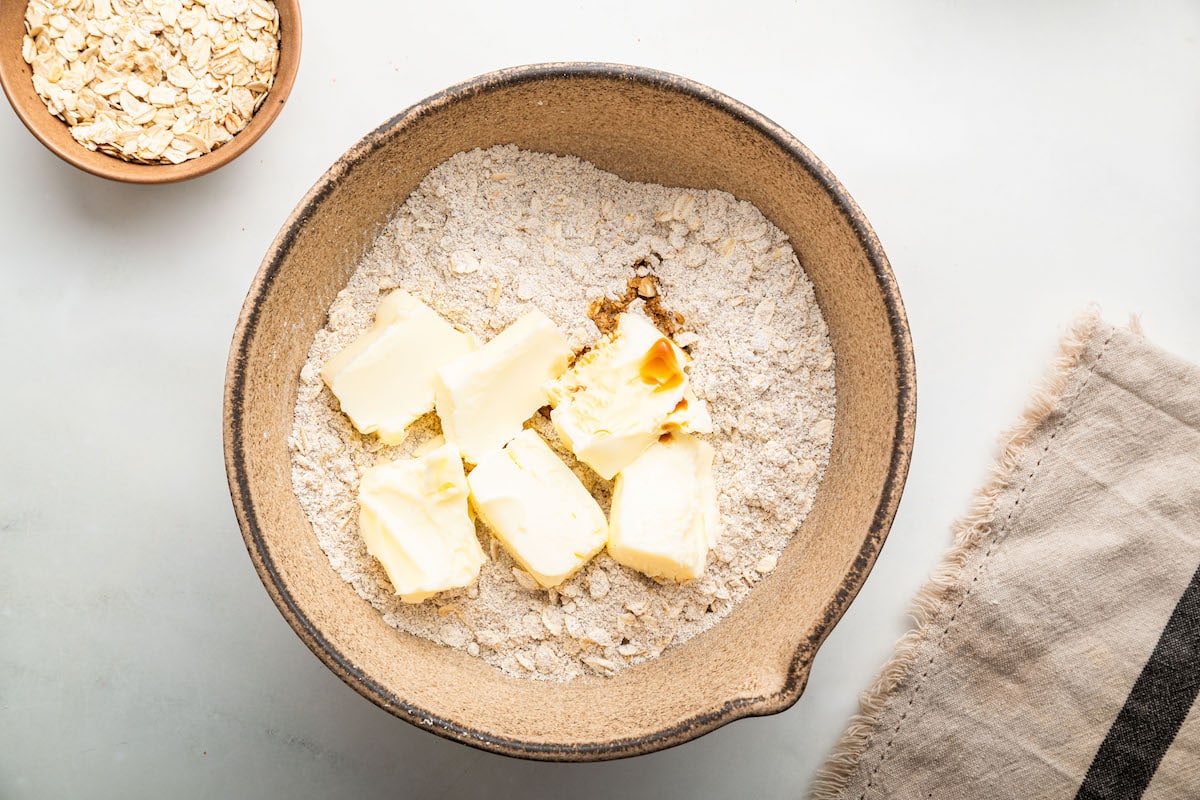 Blocks of butter added to a large bowl of dry ingredients used for date bars.