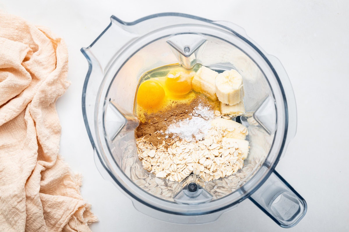 Ingredients for the greek yogurt pancakes in a blender: rolled oats, cinnamon, baking powder, salt, eggs, banana and Greek yogurt.