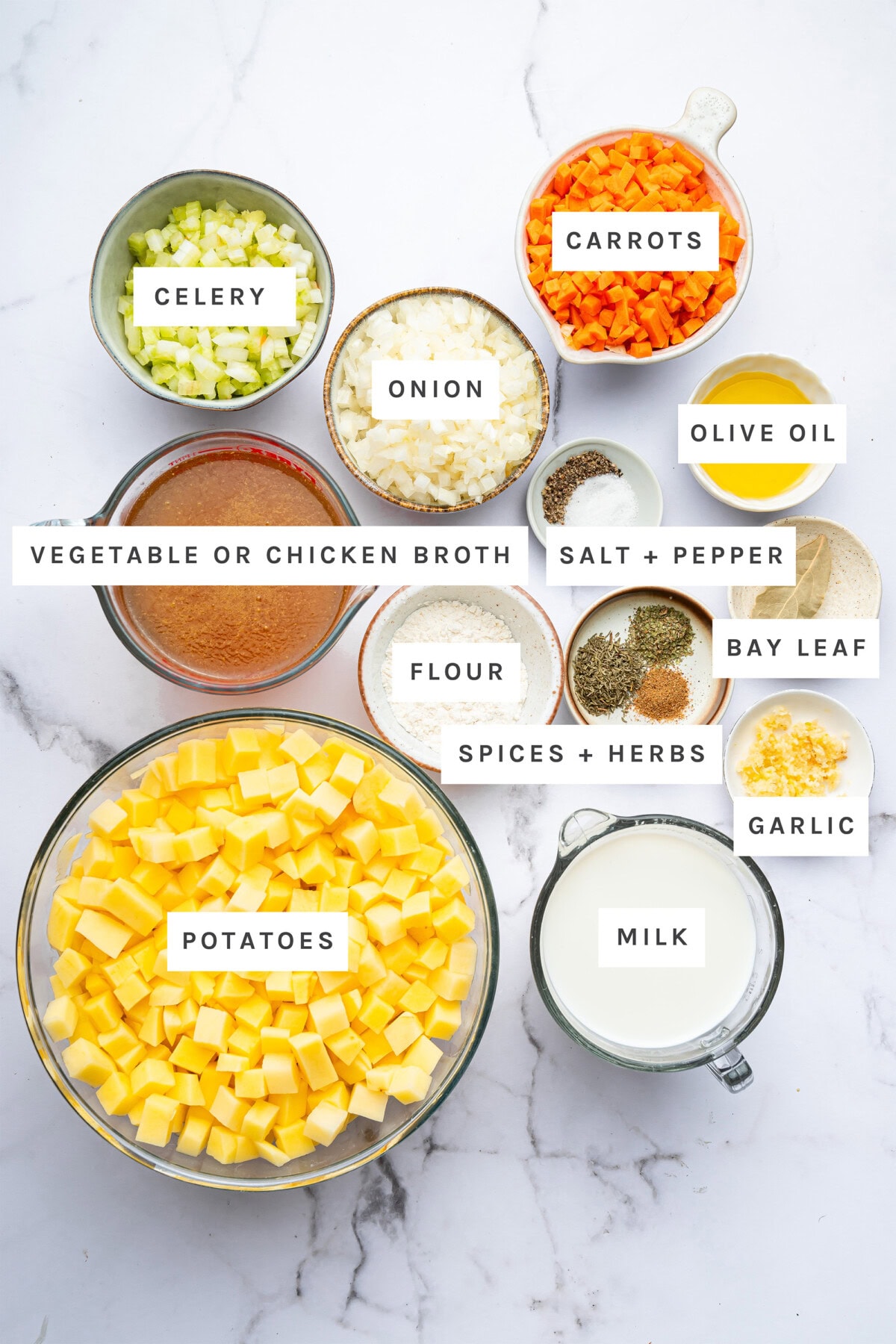 Ingredients measured out to make Potato Soup: celery, carrots, onion, vegetable or chicken broth, salt, pepper, potatoes, garlic, bay leaf, flour, olive oil, spices and herbs, and milk