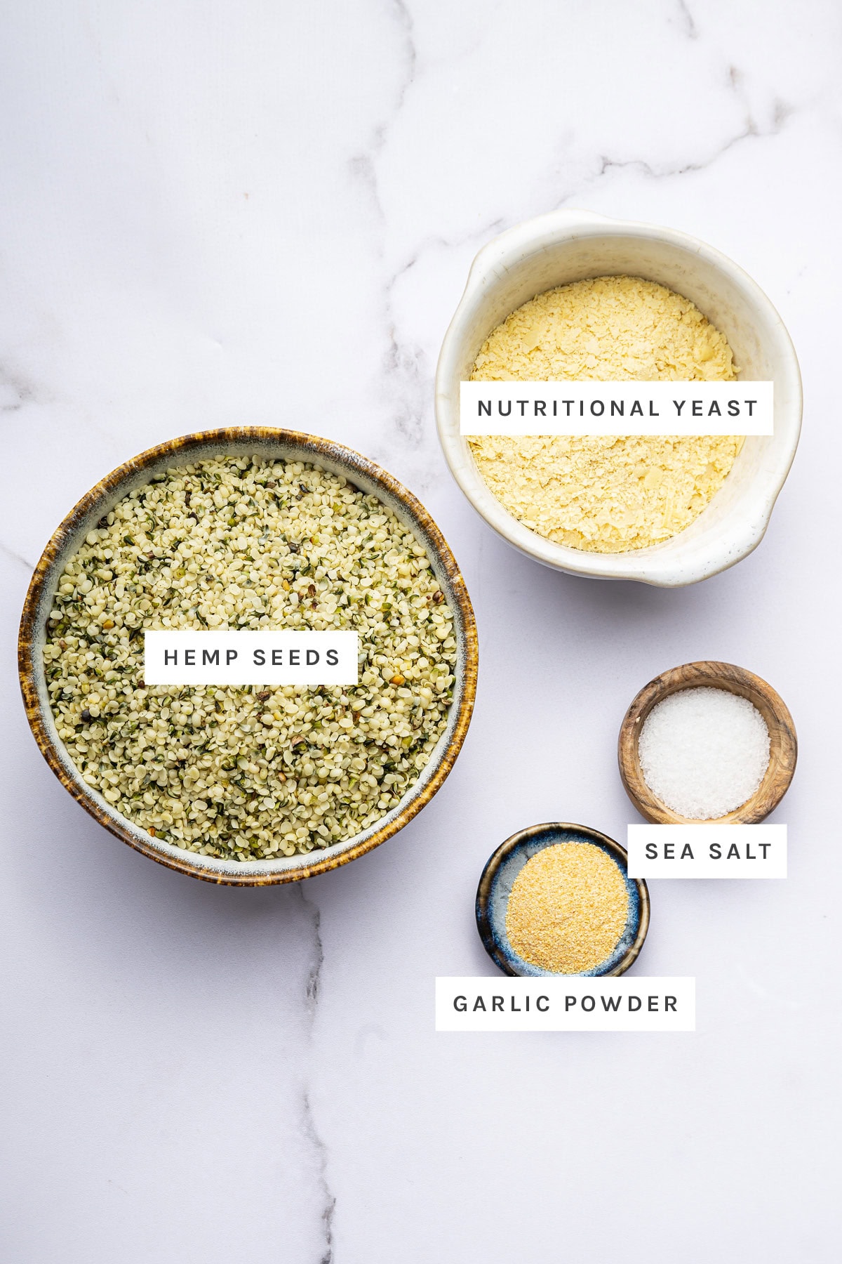 Ingredients measured out to make Vegan Parmesan Cheese: nutritional yeast, hemp seeds, sea salt and garlic powder.