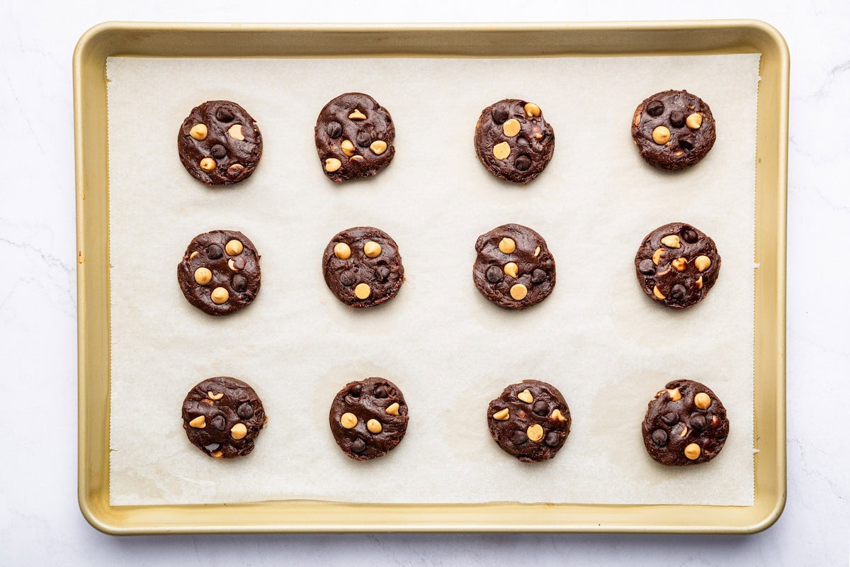 12 unbaked chocolate peanut butter cookies on a parchment-lined baking sheet.
