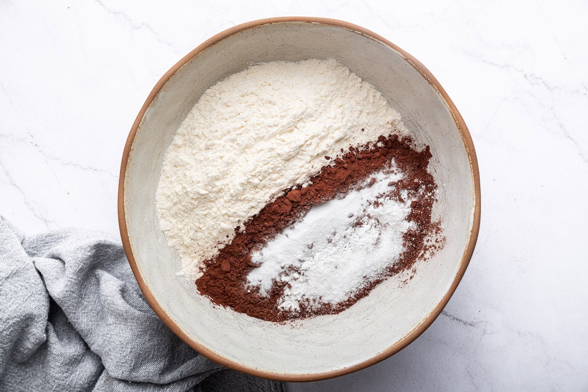 A large mixing bowl with dry ingredients used to make a healthy chocolate cake.