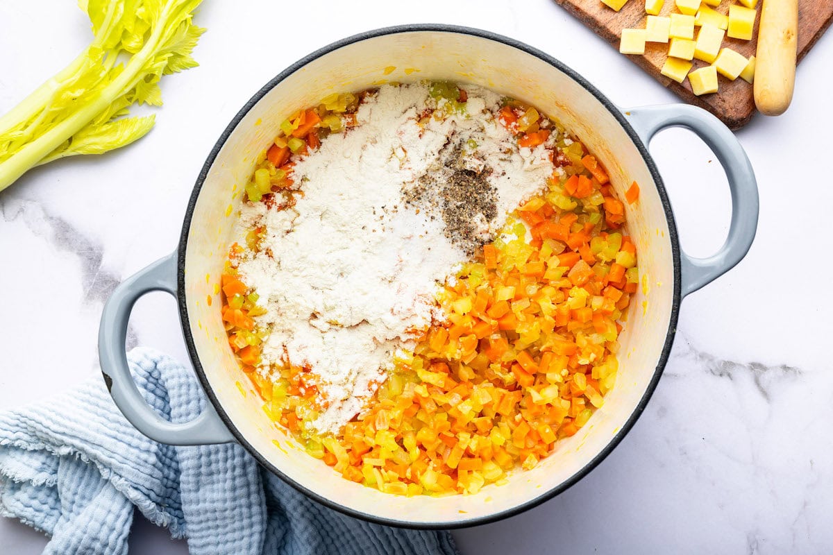 Flour, salt, pepper, dried thyme, marjoram and nutmeg added to a pot with sautéed onion, garlic, celery and carrots.