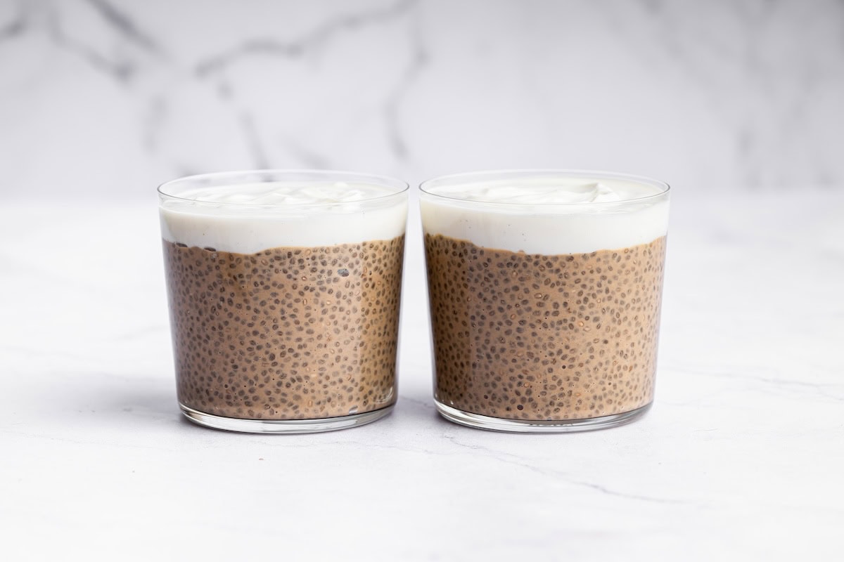 Two glass cups of tiramisu chia pudding topped with yogurt.