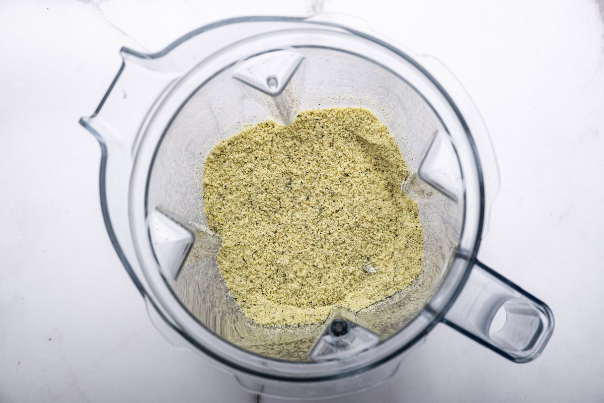 A blender with hemp seeds, nutritional yeast, salt, and garlic powder which will be used to make vegan parmesan cheese.