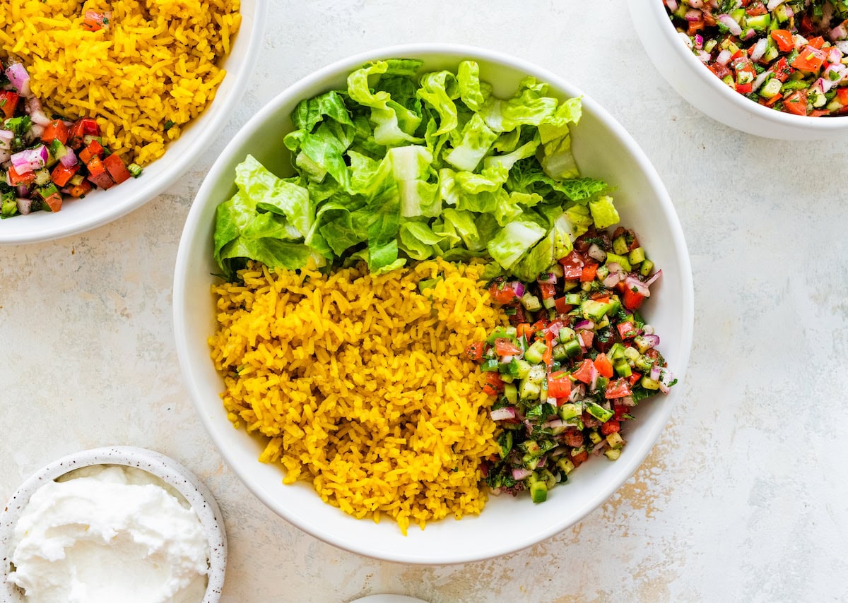 Turmeric rice, romaine lettuce and Shirazi salad in a white bowl.