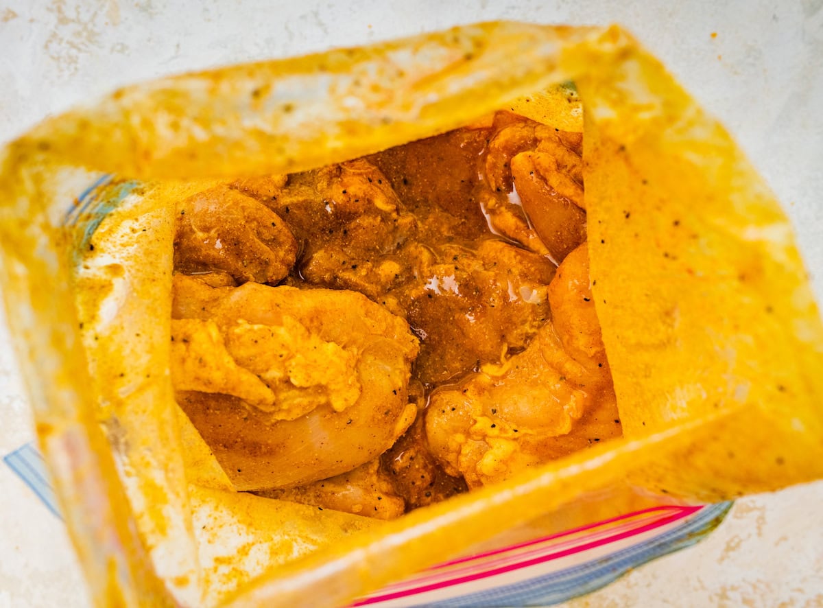 Raw chicken thighs marinating in the chicken shawarma marinade in a zip-loc bag.