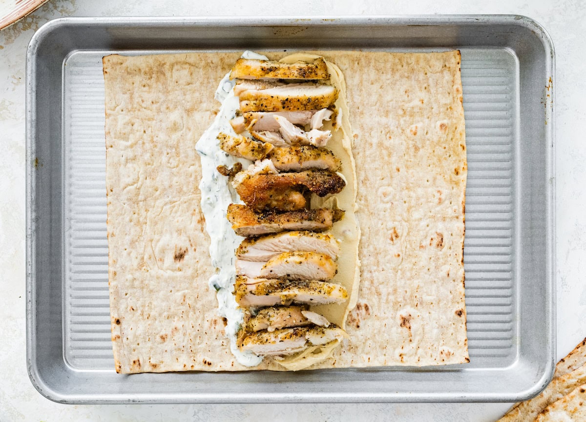 A piece of lavash bread filled with hummus, tzatziki and Greek chicken.