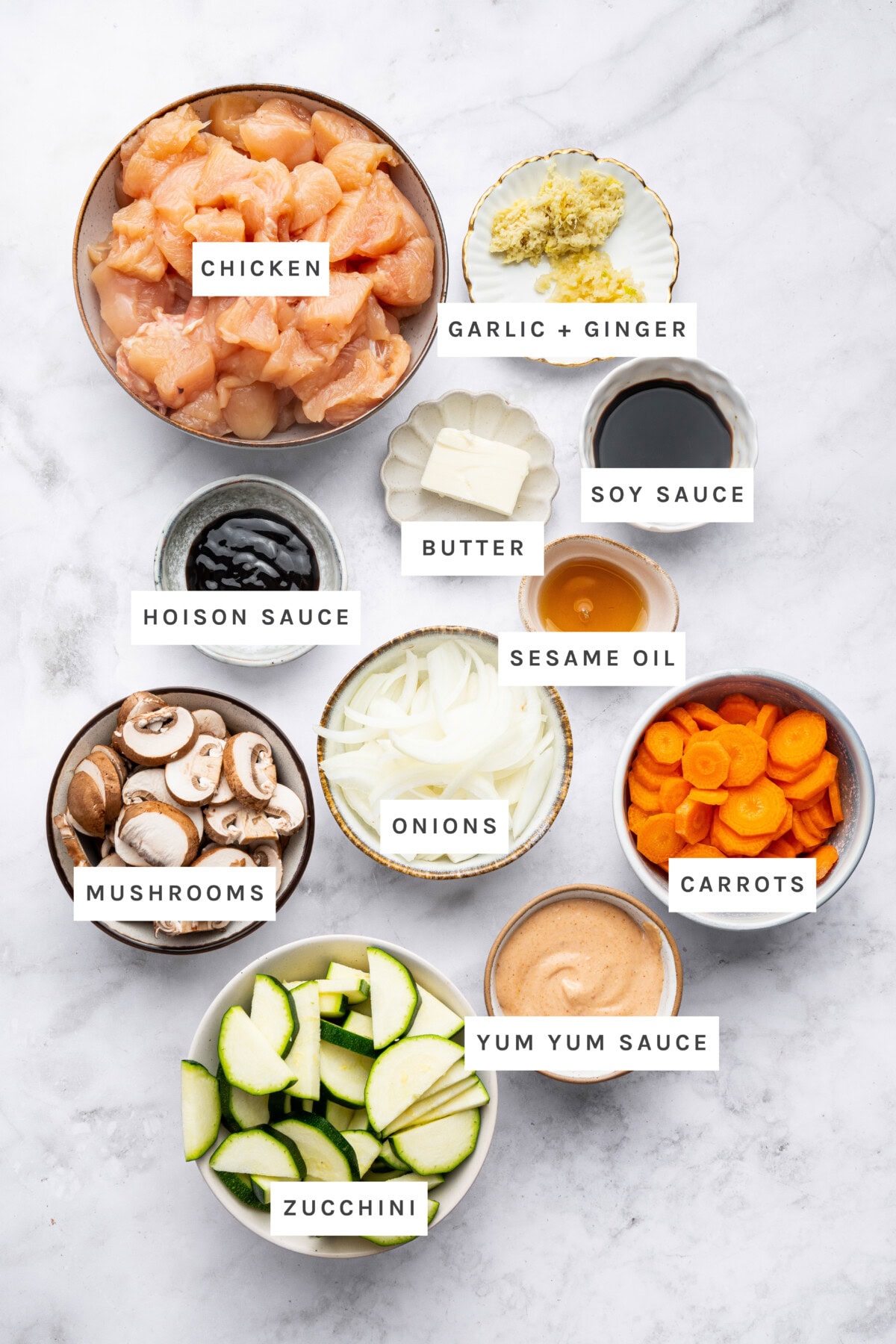 Ingredients measured out to make Hibachi Chicken: Boneless skinless chicken breast, unsalted butter, garlic, grated ginger, low sodium tamari/soy sauce, hoisin sauce, sesame oil, black pepper, zucchini, baby bella mushrooms, carrots, yellow onion