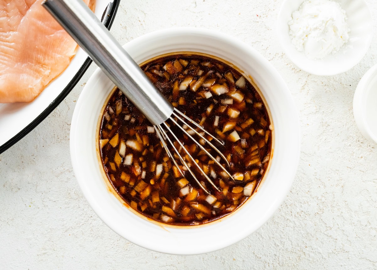 The teriyaki sauce mixed together in a small white bowl with a whisk.