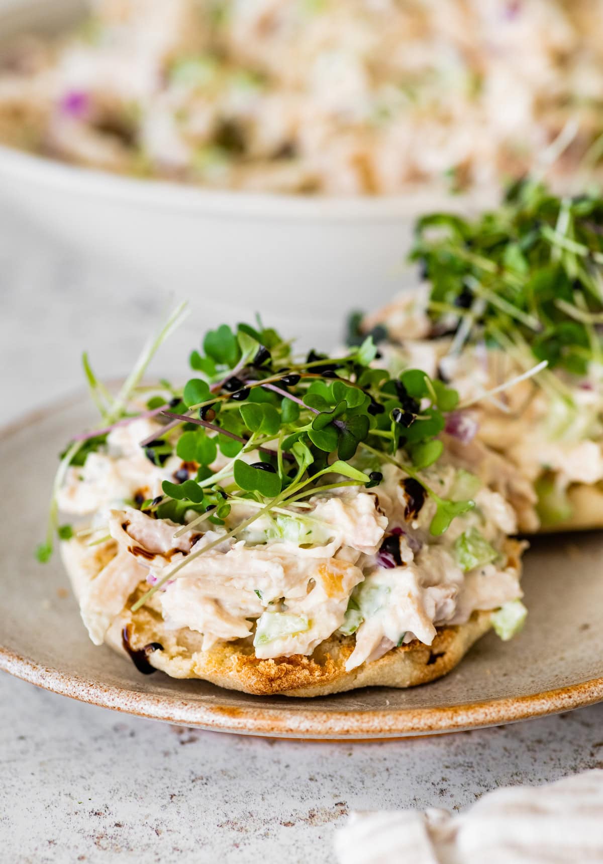 Cottage cheese chicken salad served on an English muffin topped with microgreens.