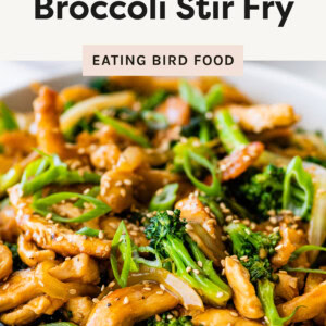 This is a delicious-looking chicken and broccoli stir fry! It seems to have tender chicken pieces, vibrant broccoli, sliced onions, and green onions, all coated in a savory sauce with sesame seeds sprinkled on top.