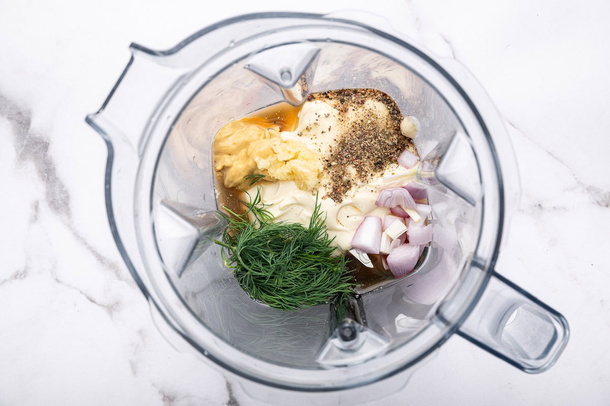 Ingredients for creamy mayo dressing in a blender with fresh dill, mayo, shallot, garlic, vinegar, mustard.