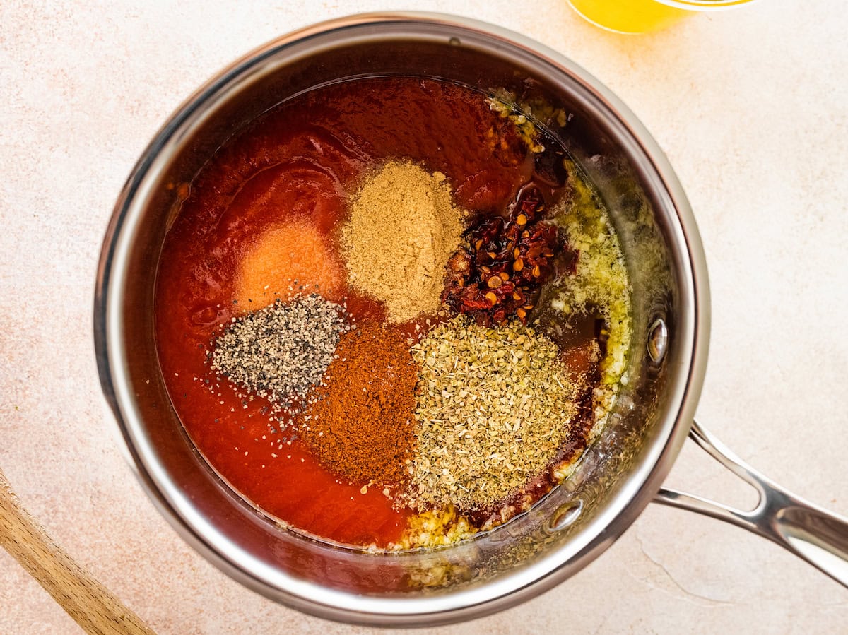 The remaining ingredients for the homemade enchilada sauce added to the pot: tomato sauce, adobo sauce, chipotle peppers and spices.