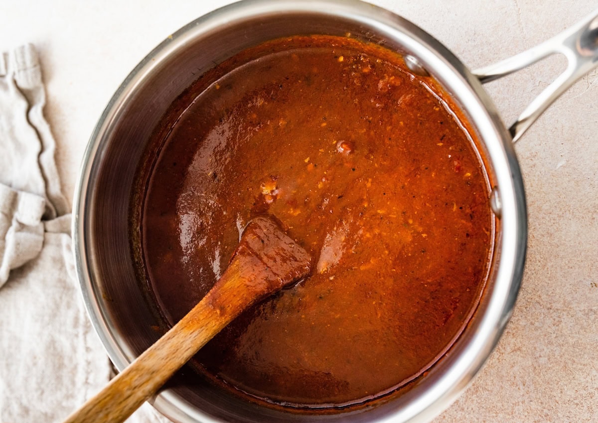 Thickened homemade enchilada sauce in a pot with a wooden spoon.