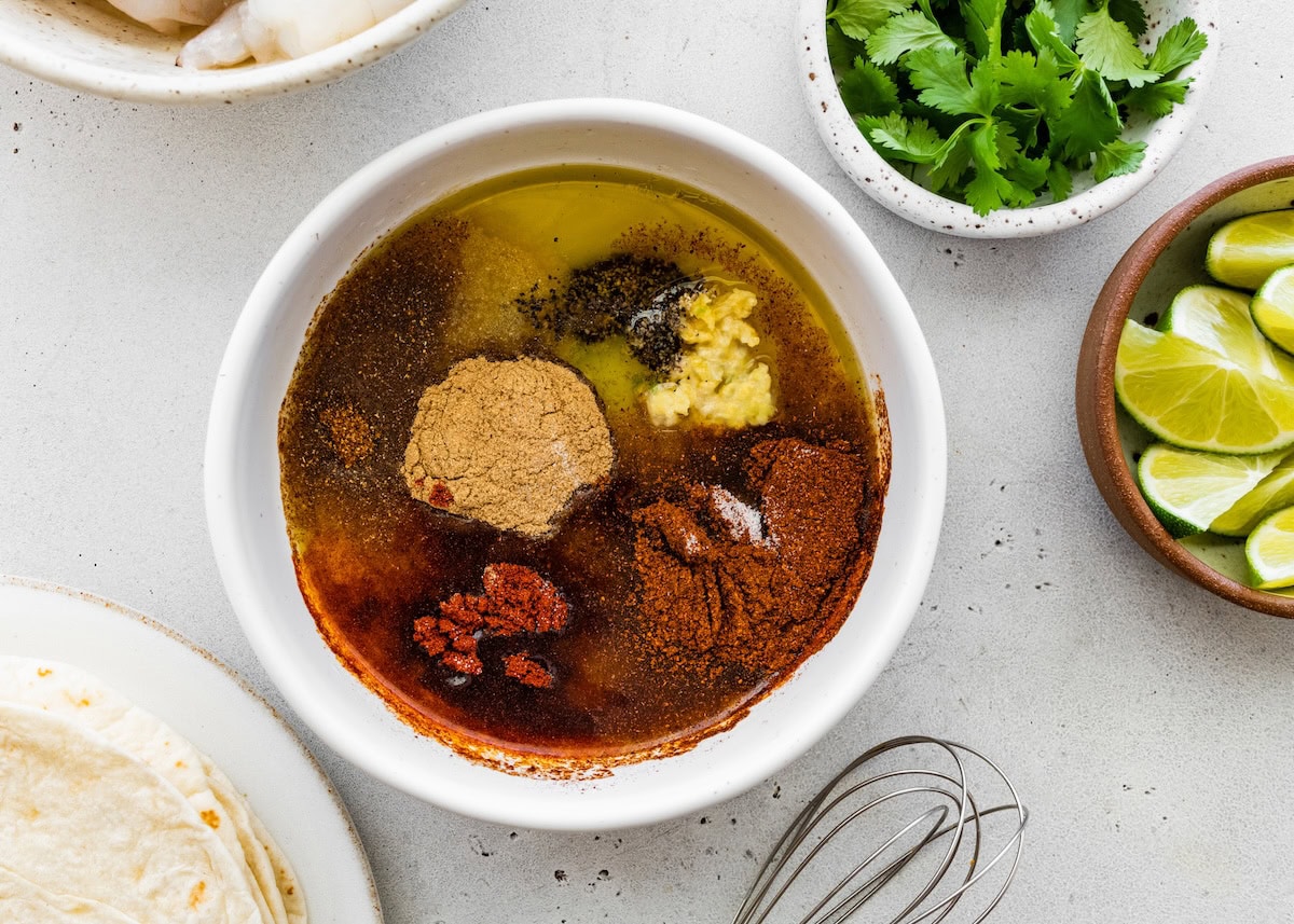 Ingredients for the shrimp marinade in a small bowl: olive oil, lime juice and a variety of spices.