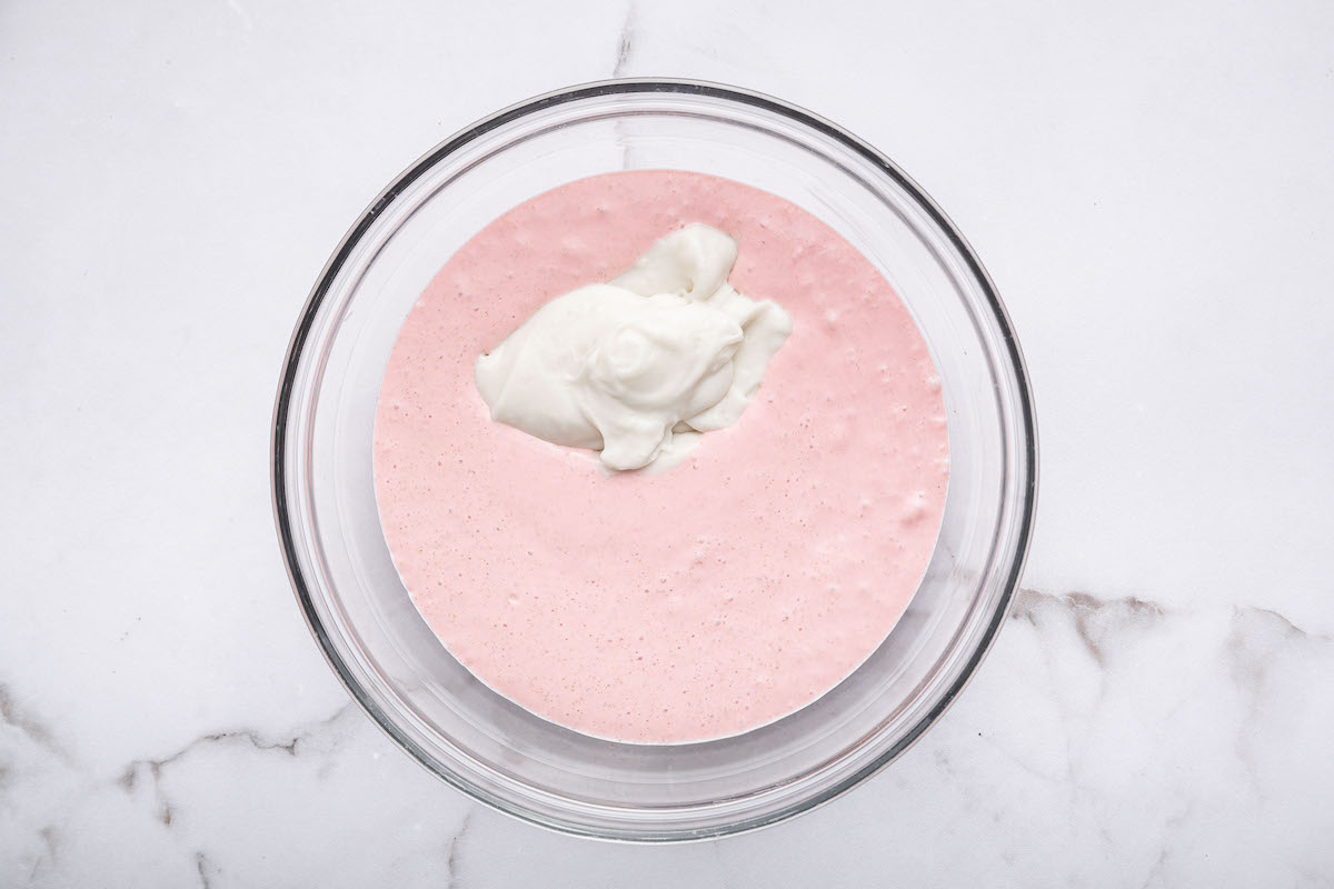 The blended strawberry cottage cheese mixture in a glass bowl with the cocowhip added to it.