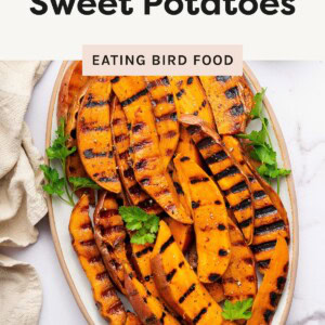 Grilled sweet potato wedges with char marks served on a platter, garnished with fresh parsley.