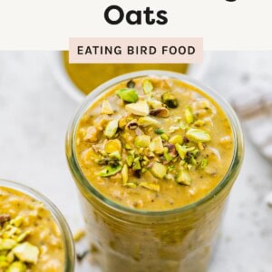Glass jar filled with high protein pistachio overnight oats topped with chopped pistachios, surrounded by other jars