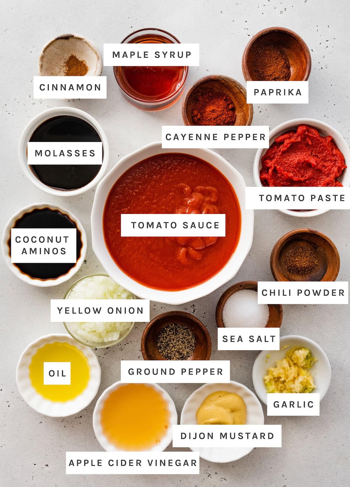 Homemade BBQ sauce ingredients: cinnamon, maple syrup, paprika, cayenne, tomato past, tomato sauce, chili powder, salt, garlic, dijon mustard, pepper, oil, yellow onion, and coconut aminos.