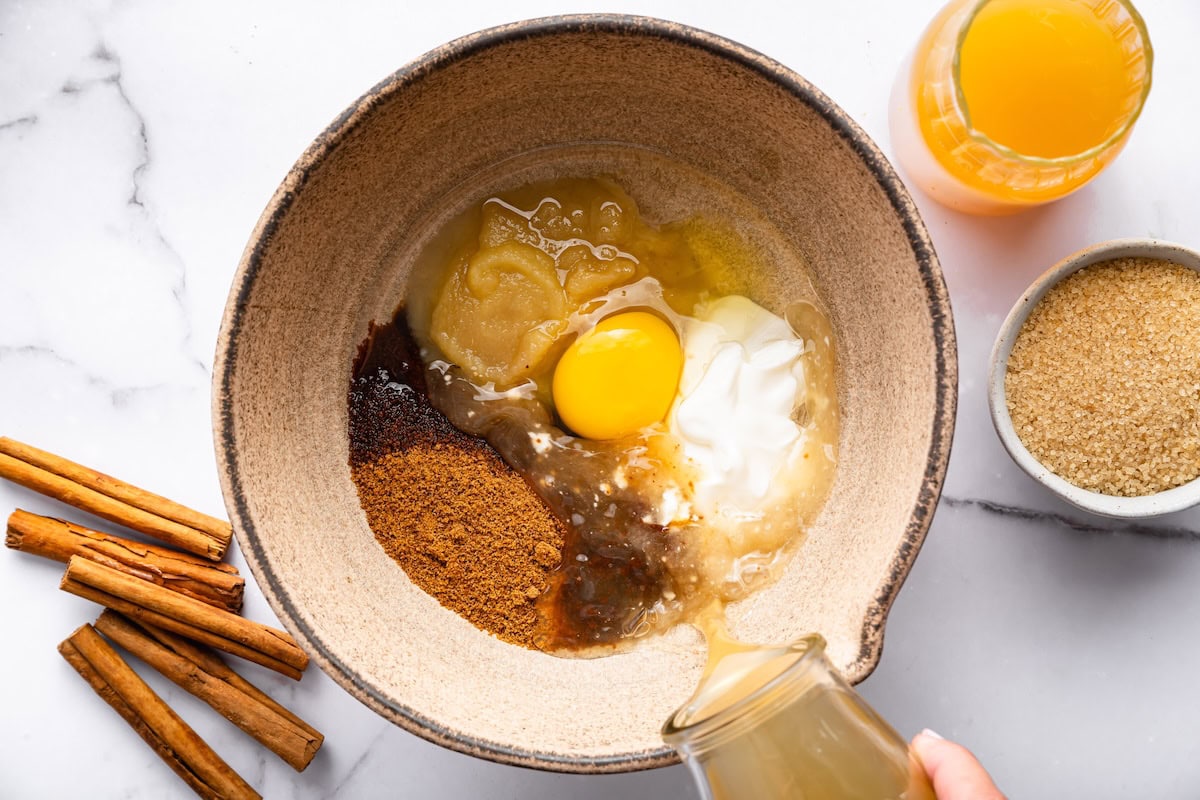 Bowl of wet ingredients including egg, applesauce, and spices being prepared for donut batter.