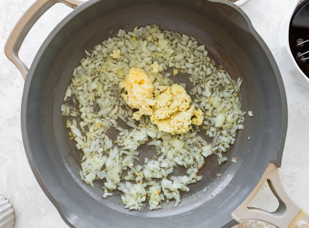 Minced garlic and ginger sautéing in a skillet with oil for chicken lettuce wrap bowls.