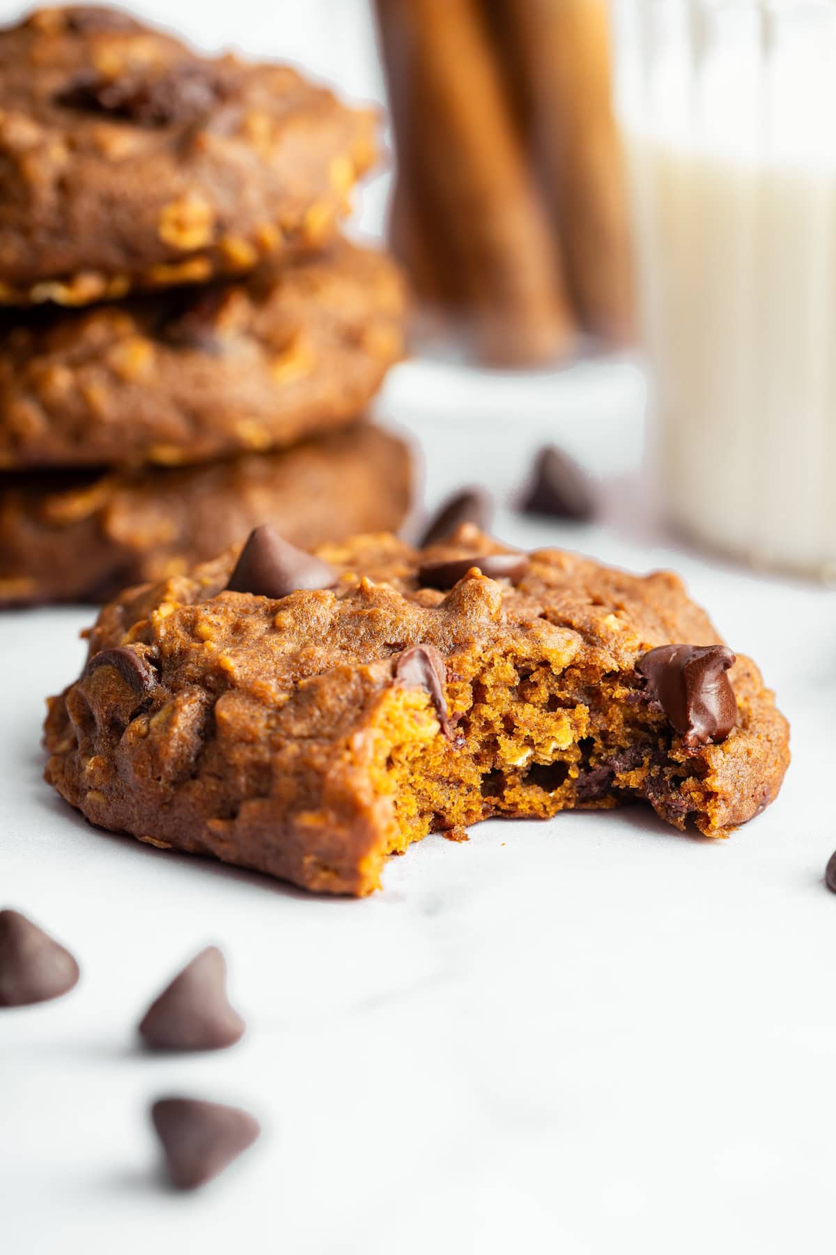 Pumpkin oatmeal cookie with a bite taken out showing soft, chewy texture.