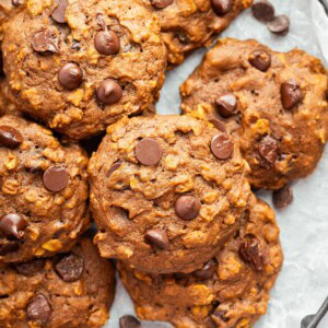 Close-up of chewy pumpkin oatmeal cookies with chocolate chips on parchment paper.
