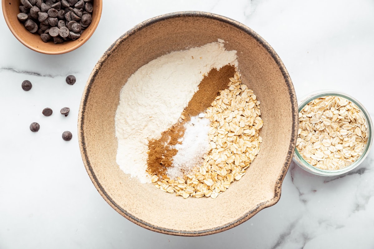 Mixing bowl with flour, oats, pumpkin pie spice, cinnamon, baking soda and salt.