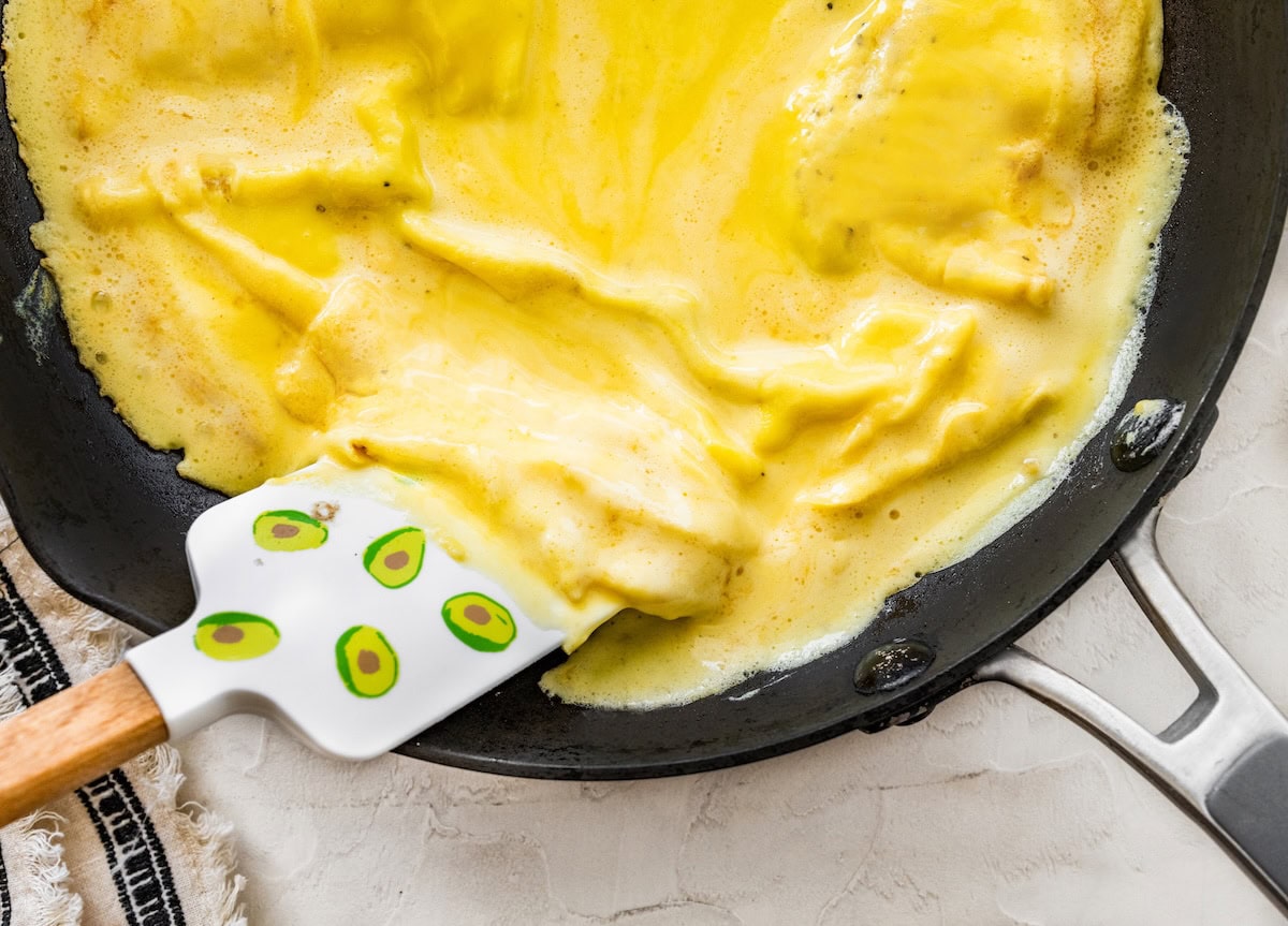 Fluffy blended egg mixture Fluffy blended egg mixture cooking in a skillet while a spatula lifts the edges.