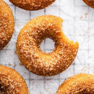 Sugar coated baked donut on parchment paper on a cooling rack.