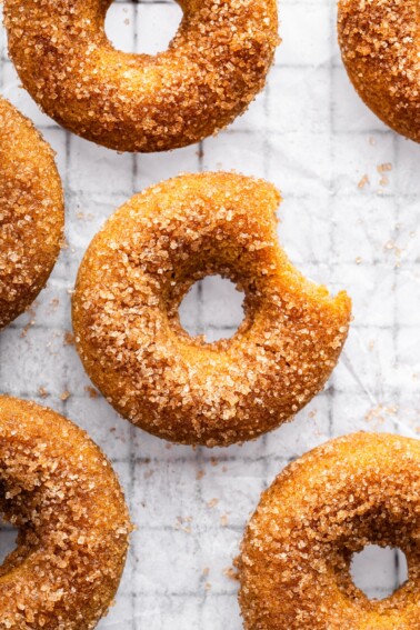 Sugar coated baked donut on parchment paper on a cooling rack.