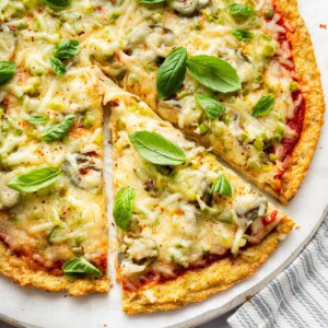 Chicken crust pizza topped with melted mozzarella and basil leaves.