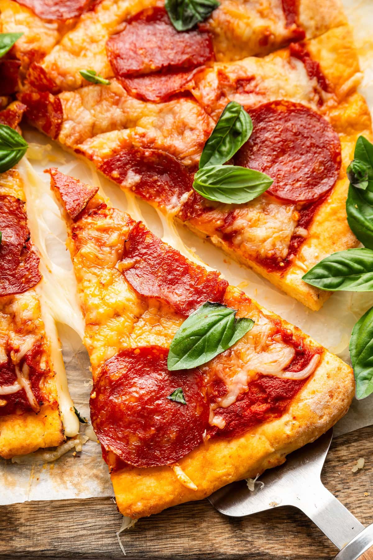 A slice of cottage cheese pizza topped with pepperoni and fresh basil.