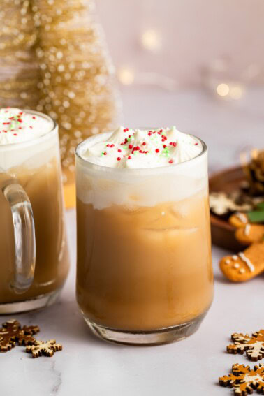 Iced sugar cookie latte topped with whipped cream and holiday sprinkles on a granite counter.