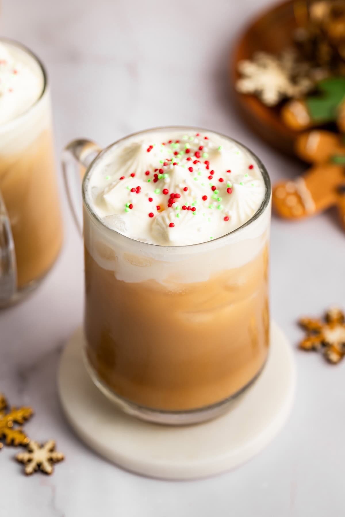 Iced sugar cookie latte recipe Iced sugar cookie latte topped with whipped cream and festive sprinkles in a clear mug.