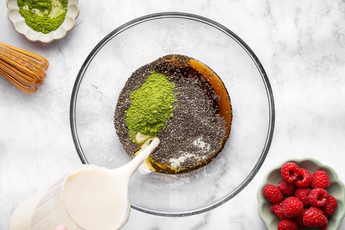 Chia seeds mixed with matcha Chia seeds mixed with matcha, almond milk, maple syrup, and vanilla in a glass bowl.