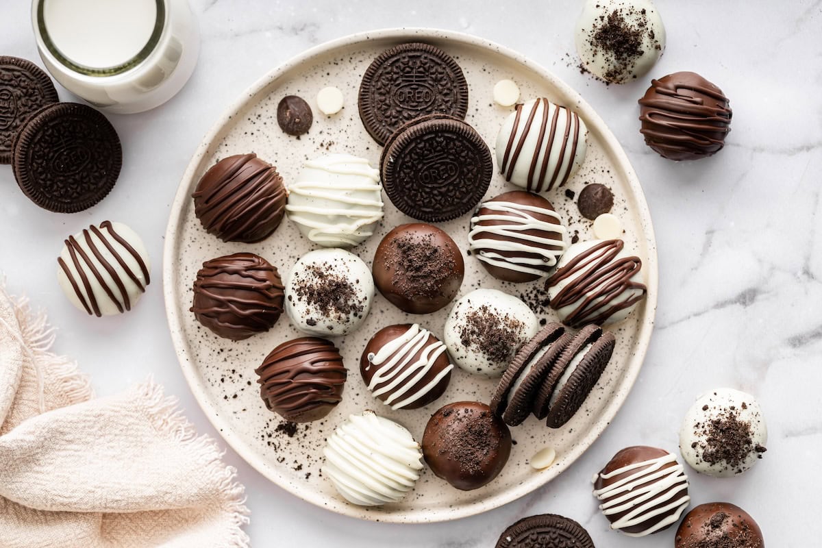 Platter of Oreo truffles topped with chocolate drizzle and Oreo crumbs.