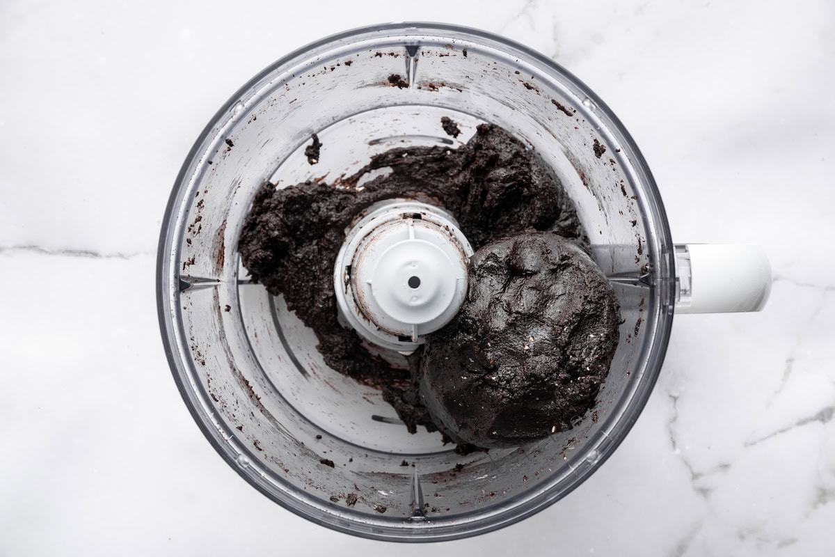 Blended Oreo truffle mixture forming a smooth dough inside a food processor.