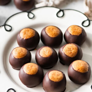 High-protein healthy buckeyes arranged on a white decorative plate with the peanut butter tops showing.