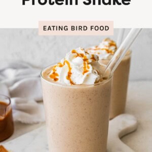 Salted caramel protein shake topped with whipped cream and caramel drizzle in a glass on a marble board