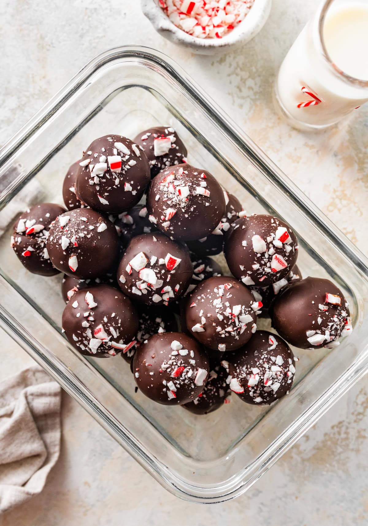 candy cane pieces Glass container filled with finished chocolate peppermint protein balls with candy cane pieces.