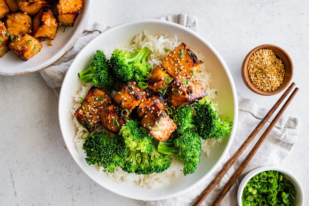 Teryaki salmon bites Teryaki salmon bites served on a plate with white rice and broccoli.