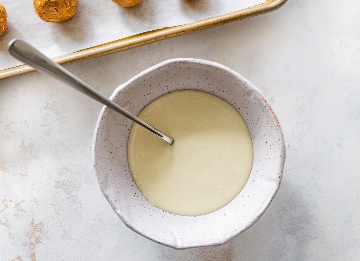melted white chocolate Bowl of melted white chocolate with a spoon, ready for drizzling over gingerbread protein balls.