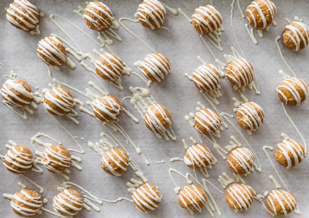 drizzled with white chocolate Gingerbread protein balls on a sheet pan drizzled with white chocolate and ready to chill.